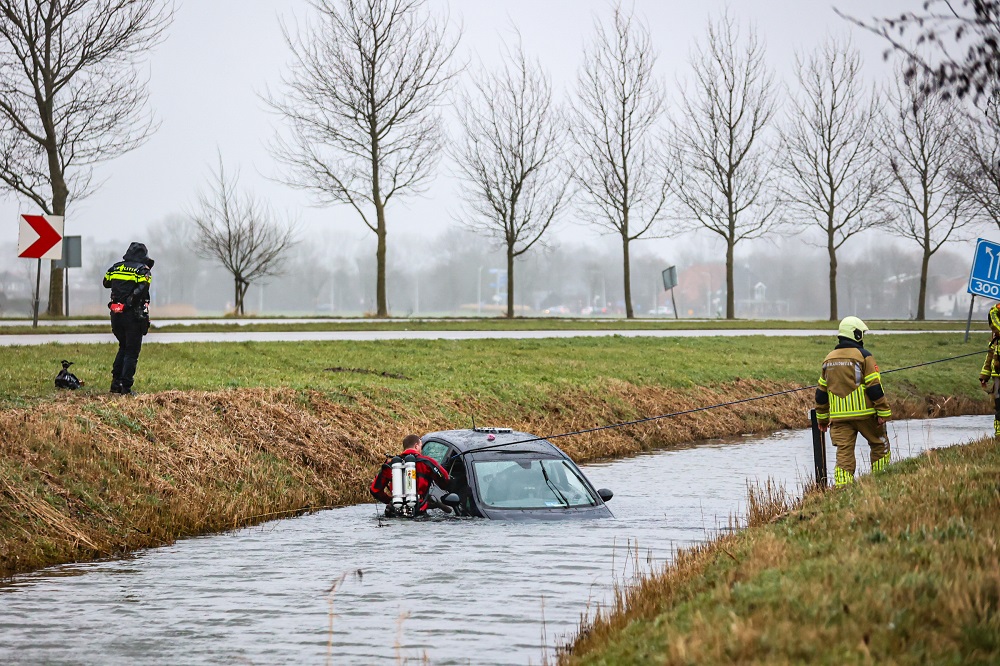 Auto te water, brandweer redt bestuurder
