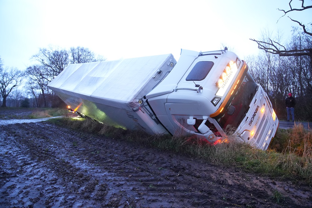 Vrachtwagen belandt in greppel, chauffeur ongedeerd
