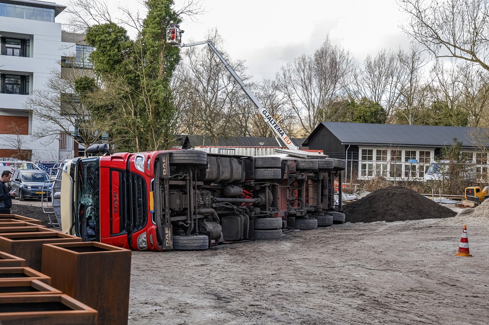 Vrachtwagen gekanteld op bouwplaats, chauffeur gewond
