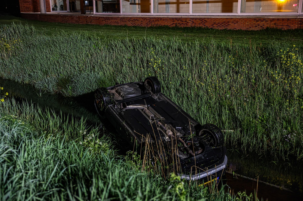 Auto op z’n kop in sloot, bestuurder met politie mee