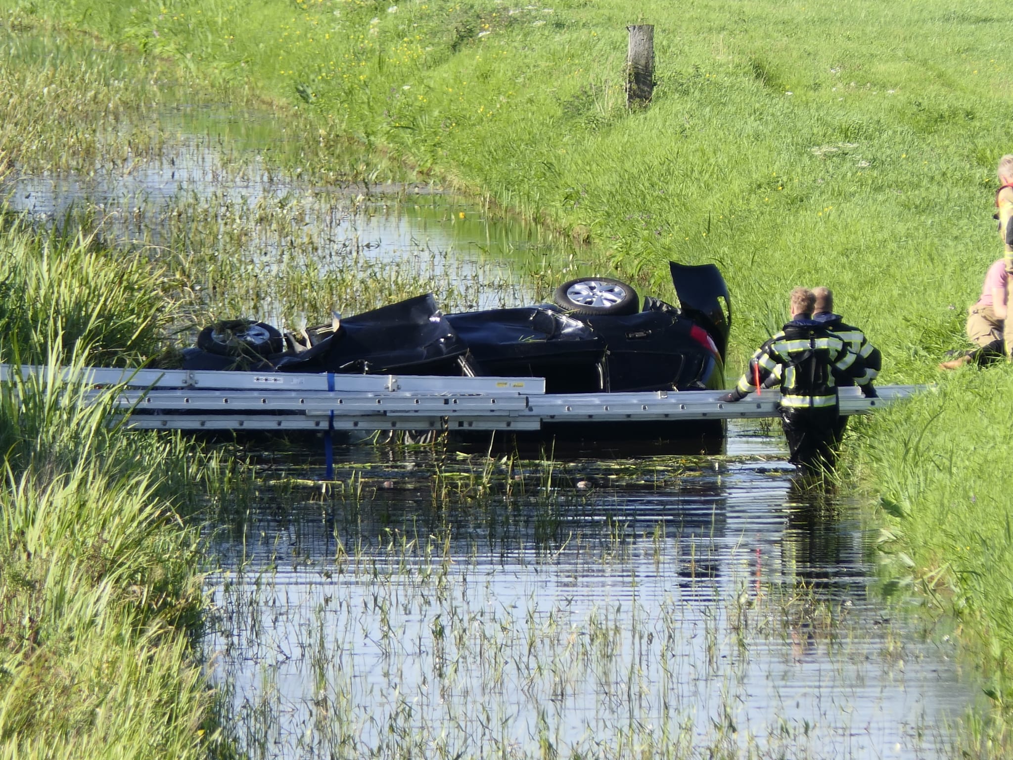 Heldhaftige redding na auto te water naast snelweg