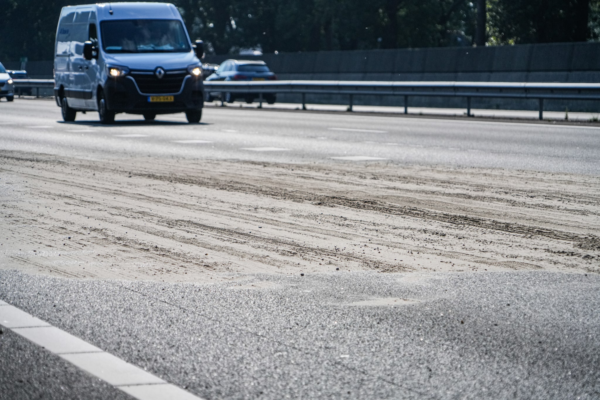 Aanhanger schaart op snelweg, lading zand en steentjes op rijbaan