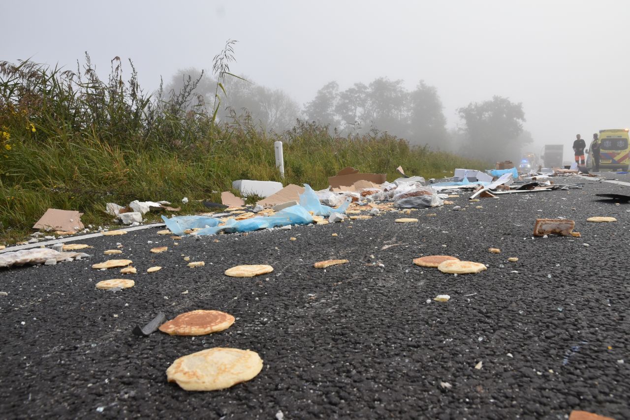 Twee vrachtwagens botsen, weg bezaaid met etenswaren