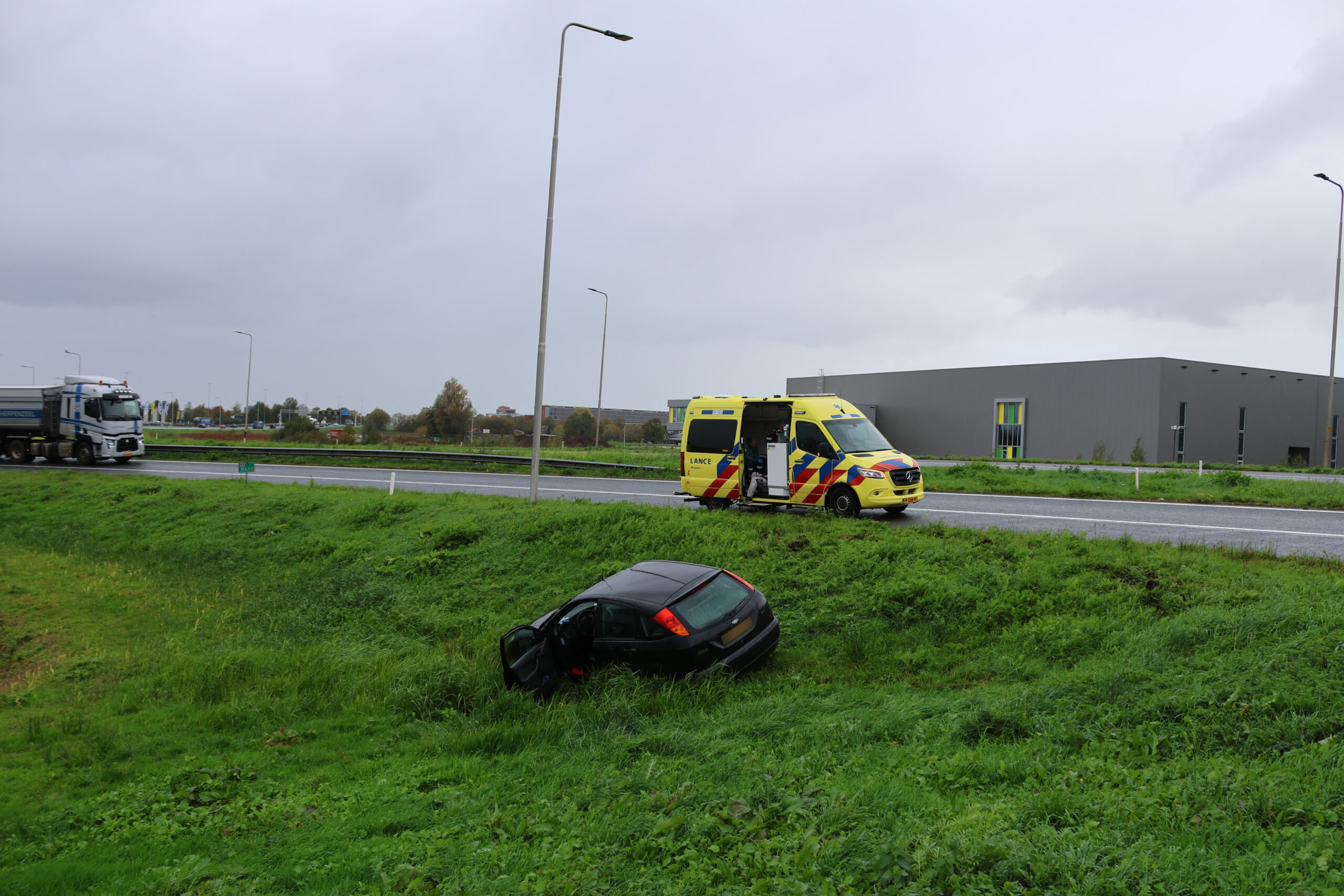 Auto glijdt van talud bij afrit snelweg, bestuurder naar ziekenhuis