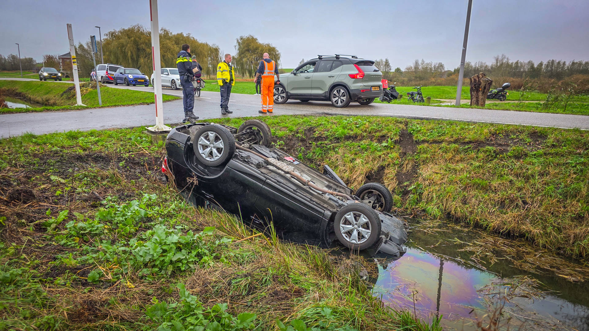 Auto op kop in sloot, omstanders redden drie inzittenden