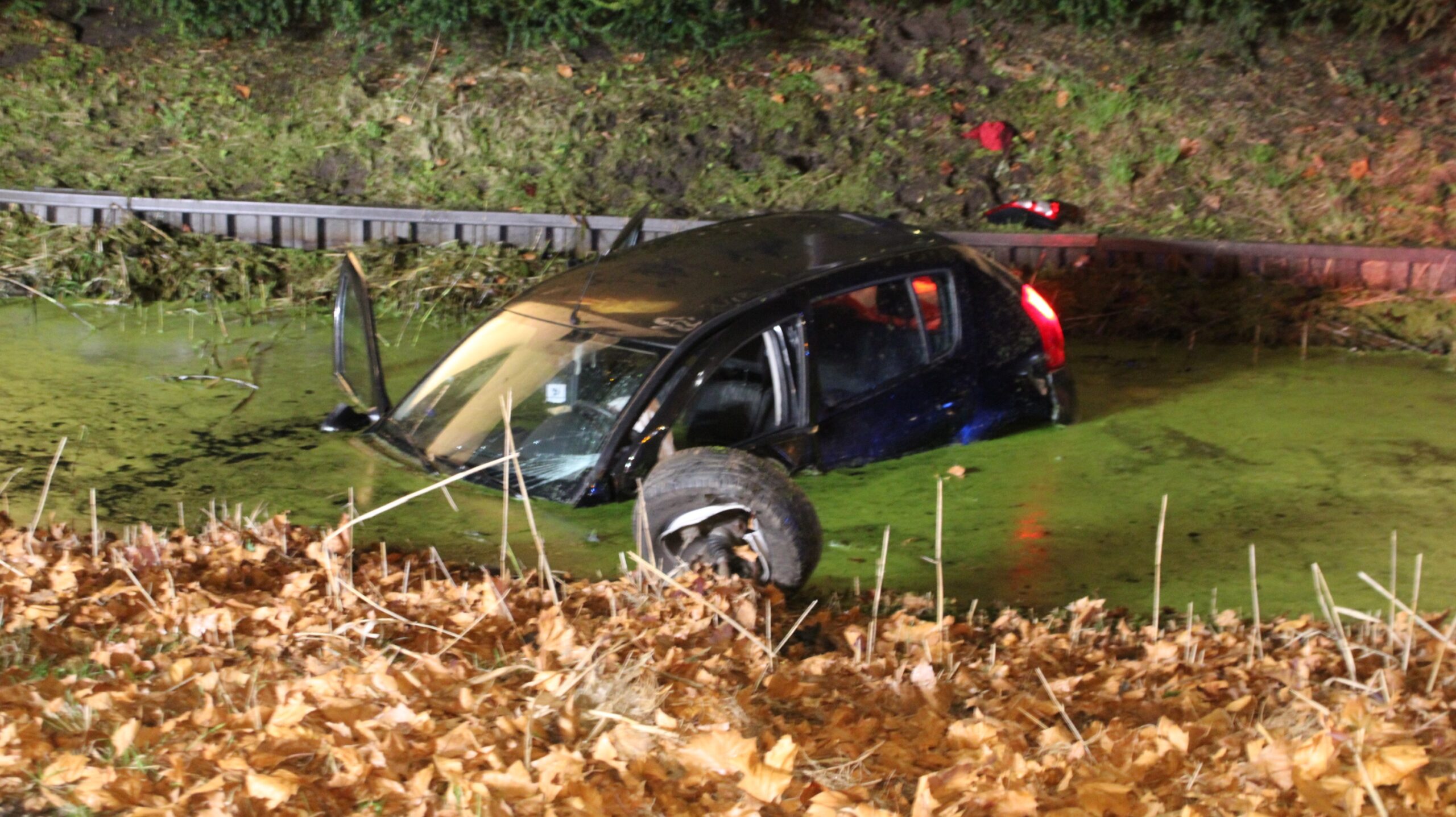 Auto botst tegen boom en belandt in water, drie gewonden