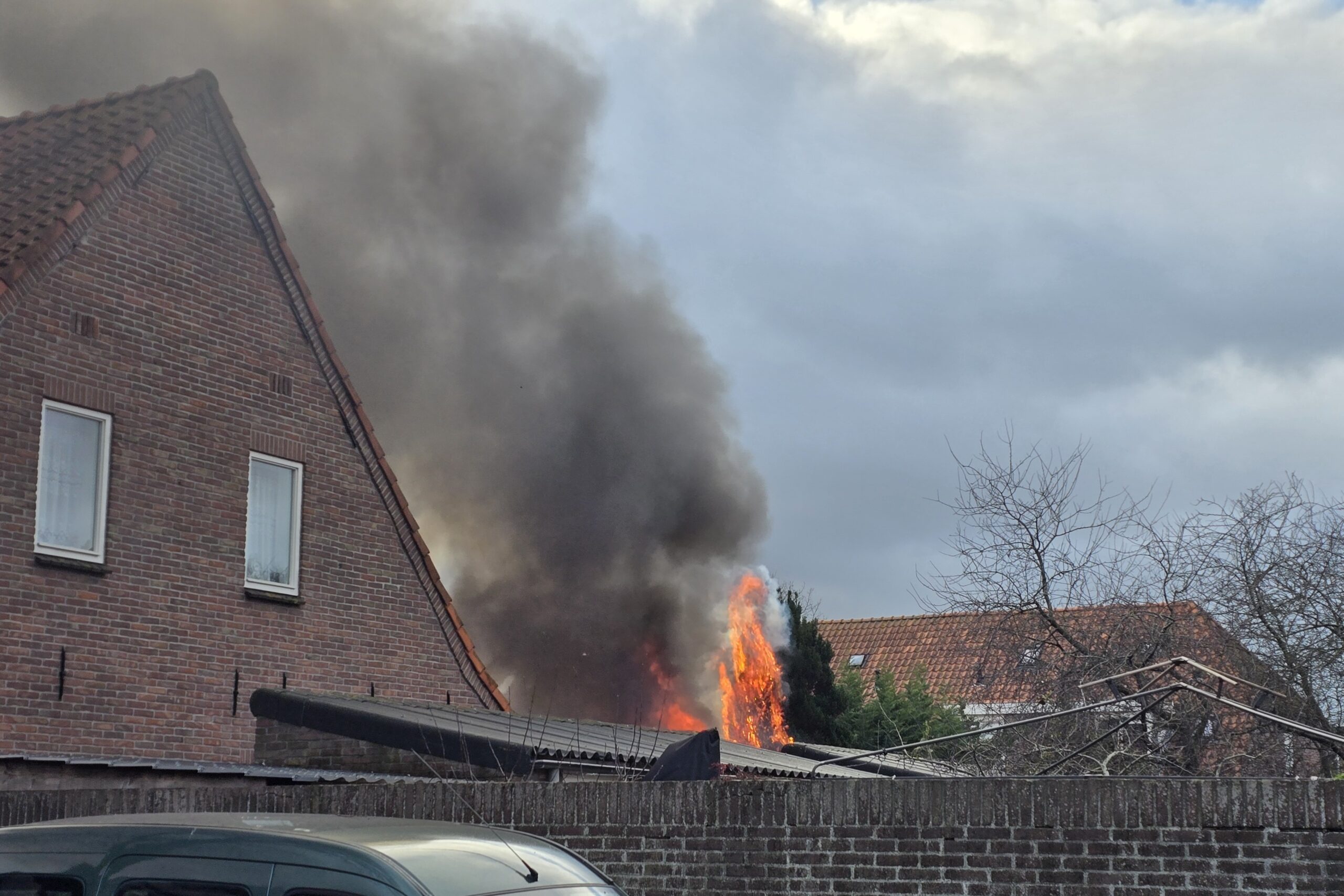 Brand in dak bijgebouw met explosies, vrouw op tijd in veiligheid