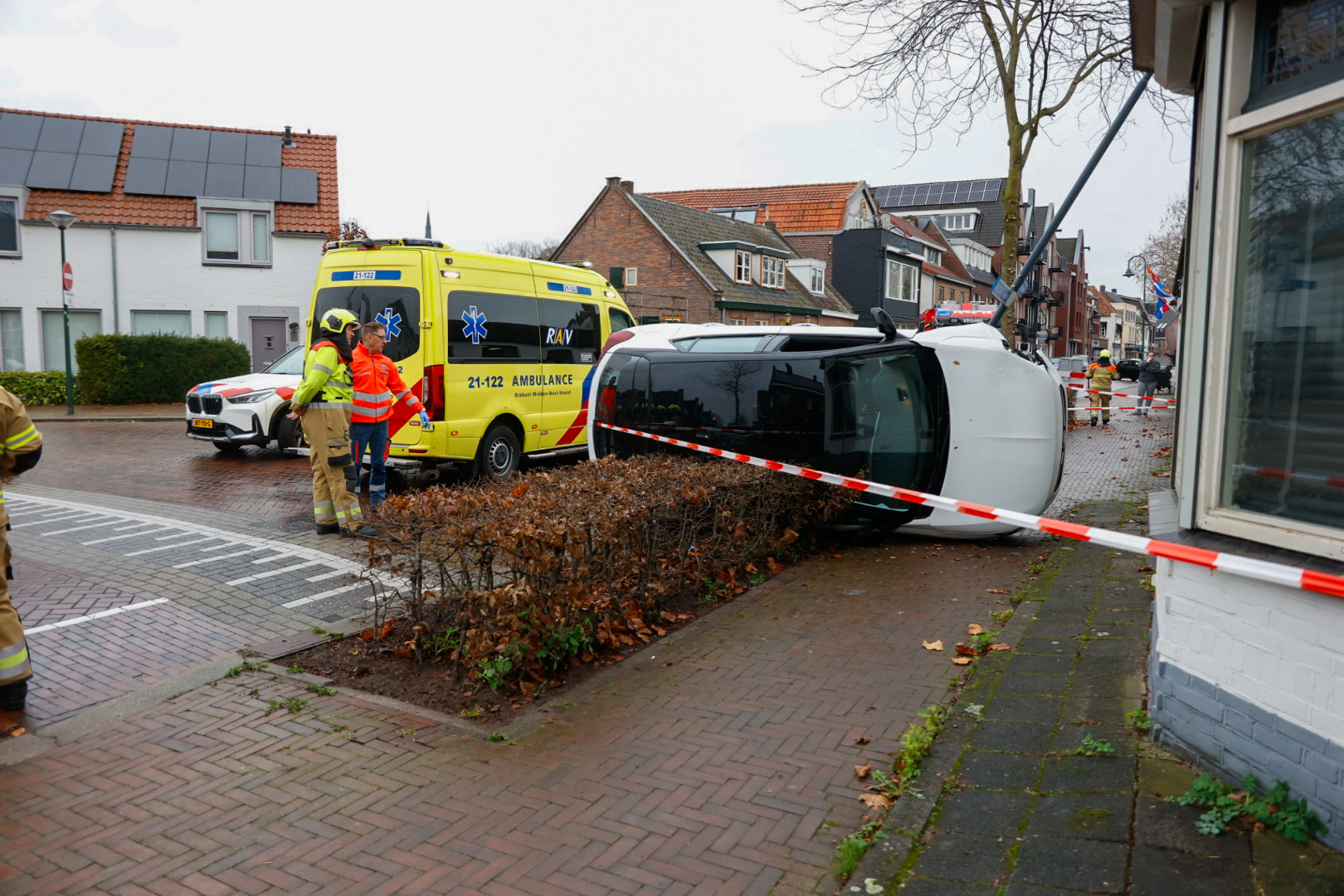 Auto op zijn kant na botsing tegen lantaarnpaal