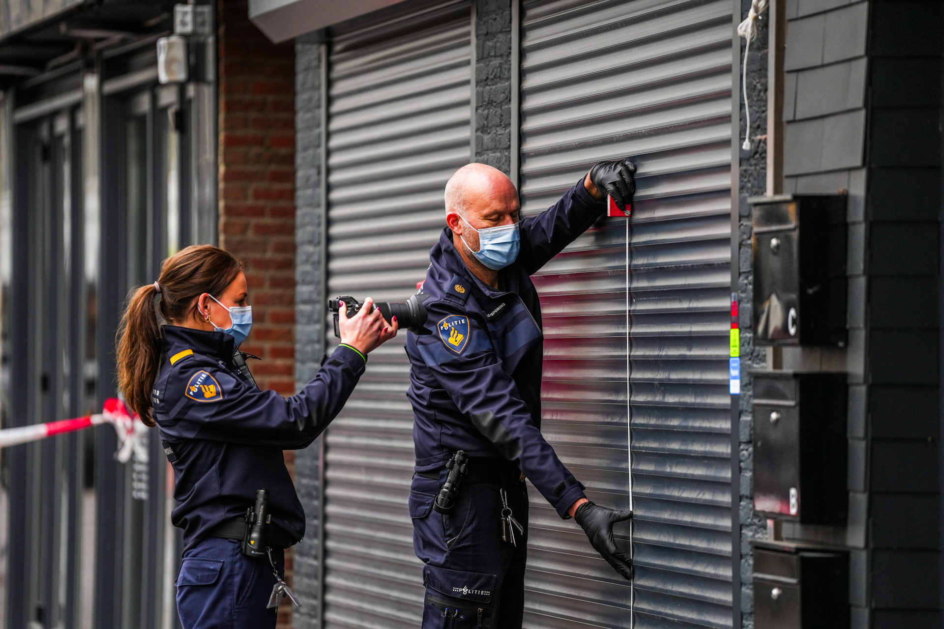 Kogelhulzen en gat in rolluik bij fastfoodzaak
