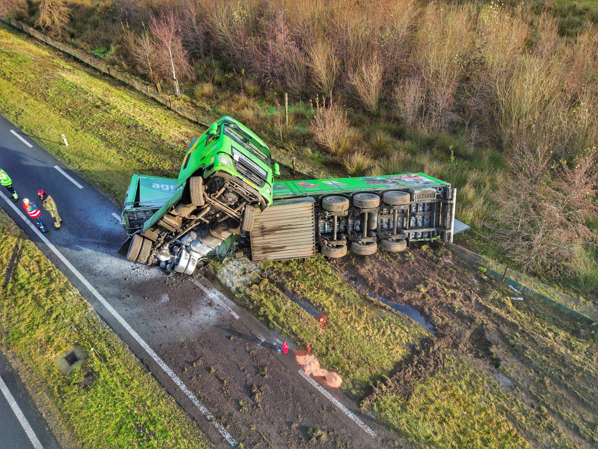 Vrachtwagen met houtsnippers slaat om, weg dicht