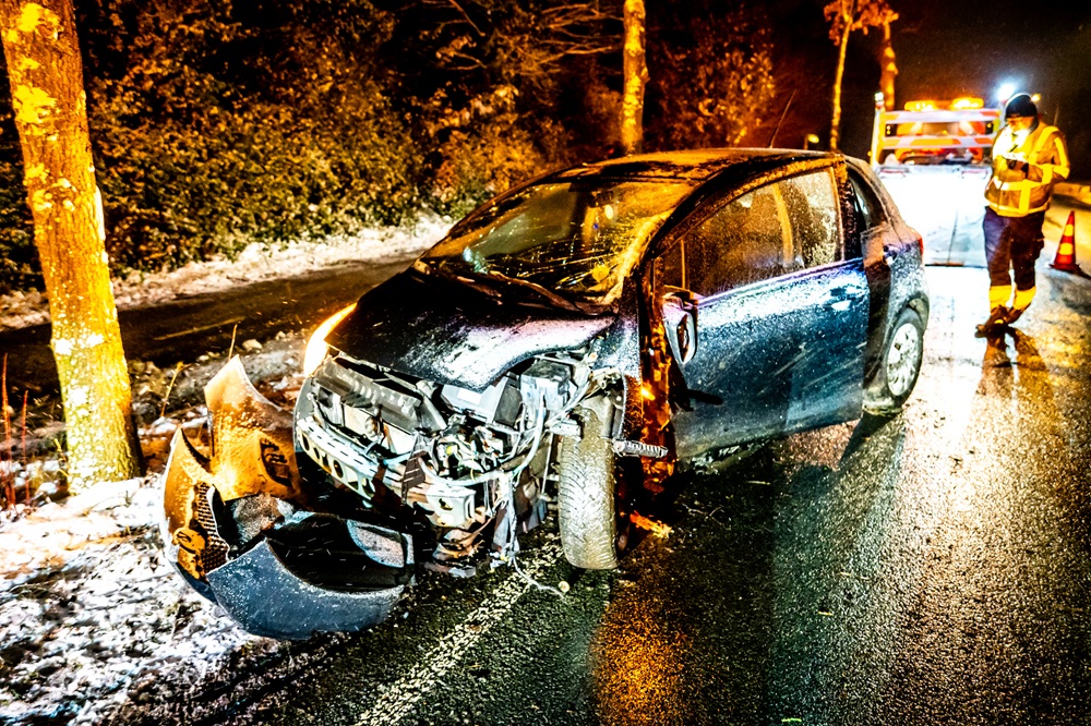 Auto door gladheid van de weg en botst tegen boom