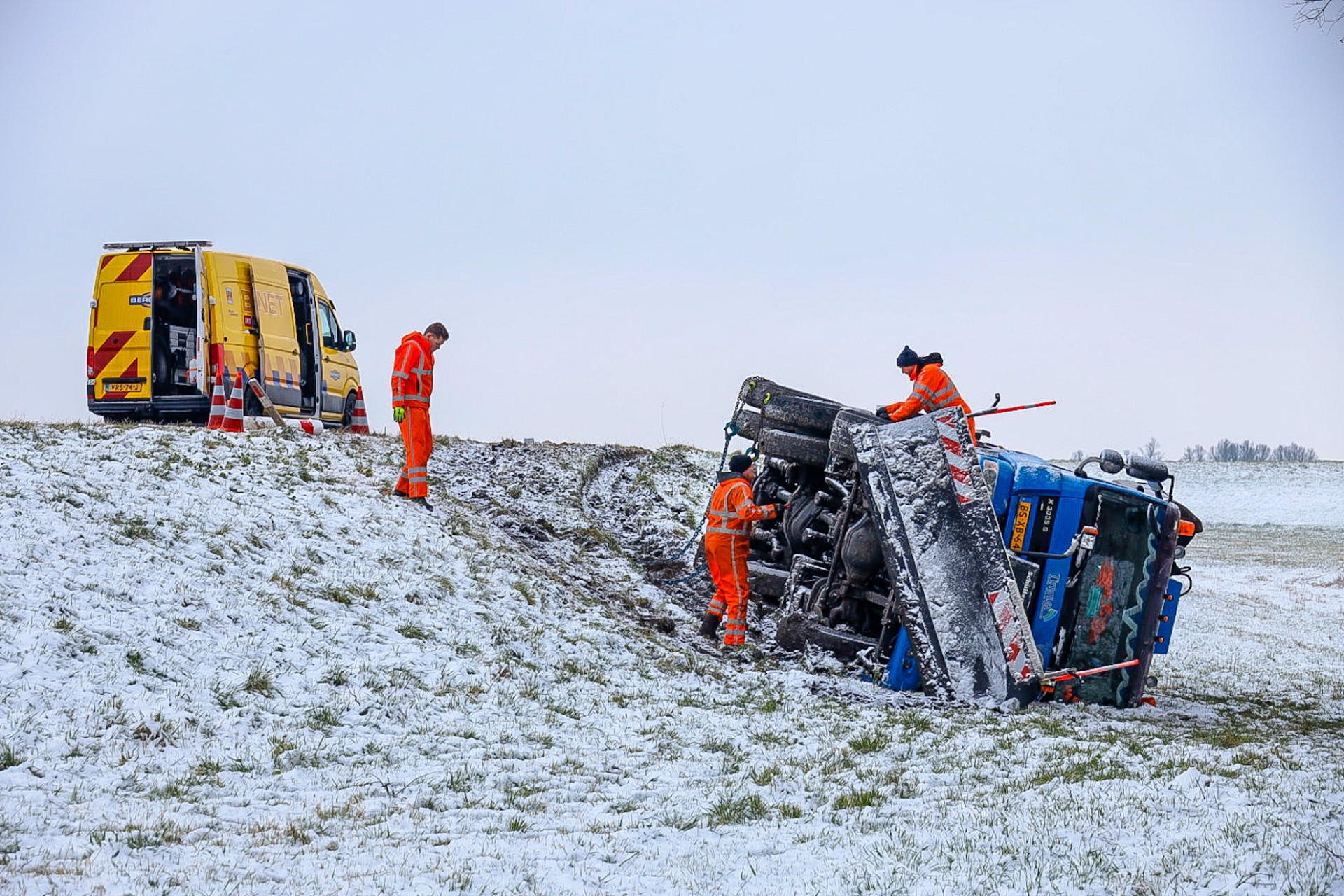 Strooiwagen glijdt van weg en belandt op zijkant