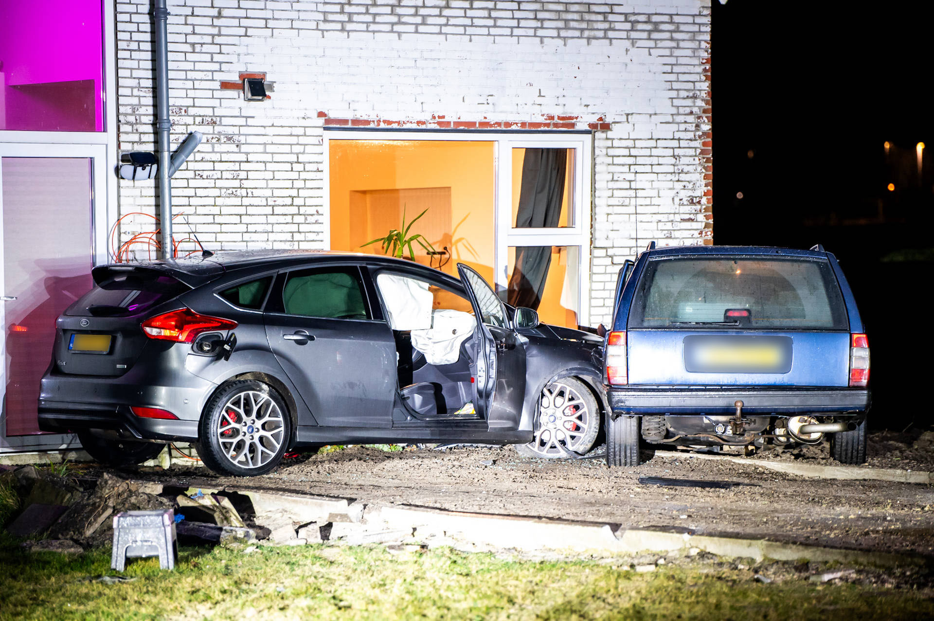 Twee voertuigen belanden tegen woning, bestuurder gevlucht