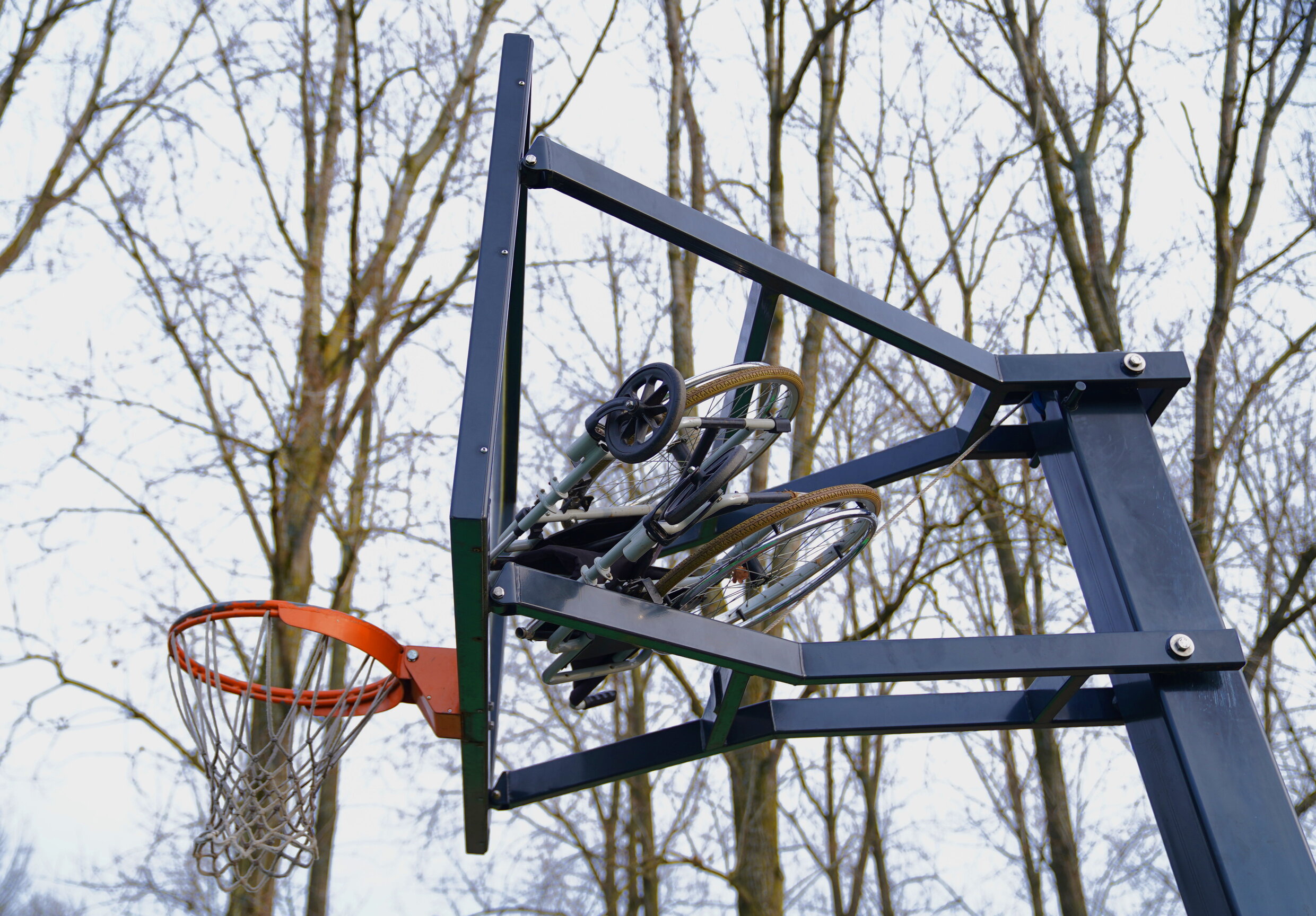 Rolstoel op basketbalpaal gegooid