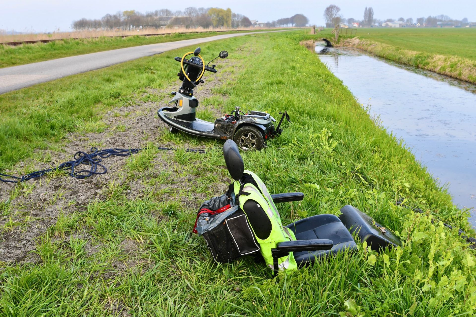 Persoon met twee hondjes op scootmobiel raakt te water