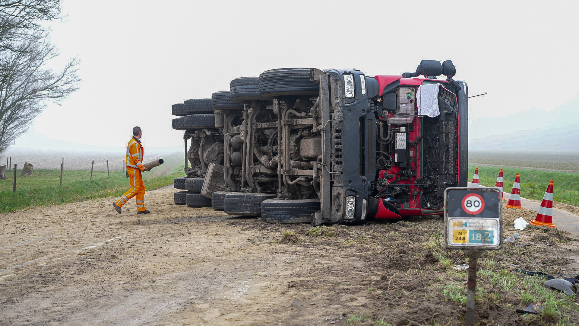 Vrachtwagen vol zand kantelt, chauffeur naar ziekenhuis