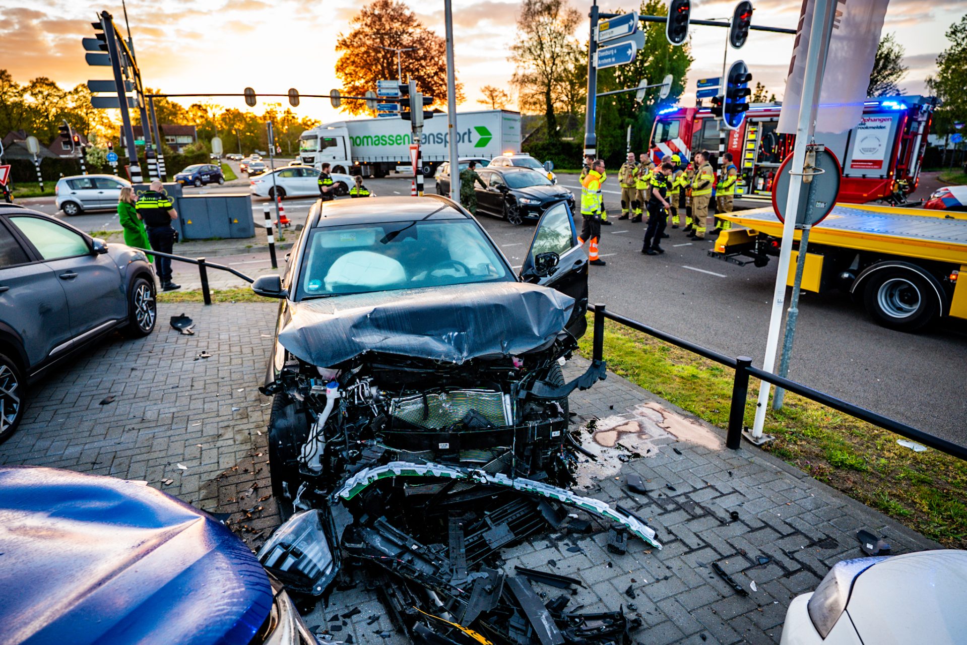Gewonde bij botsing op kruising, auto rijdt door hekwerk autobedrijf