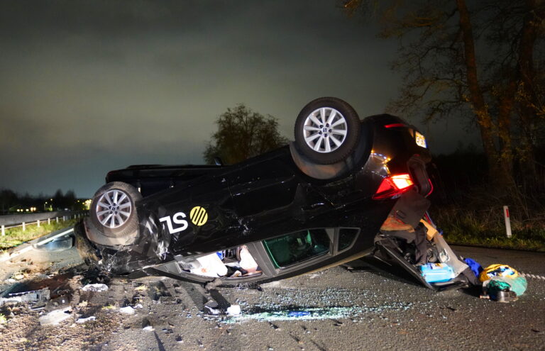 Auto over de kop na aanrijding, twee gewonden