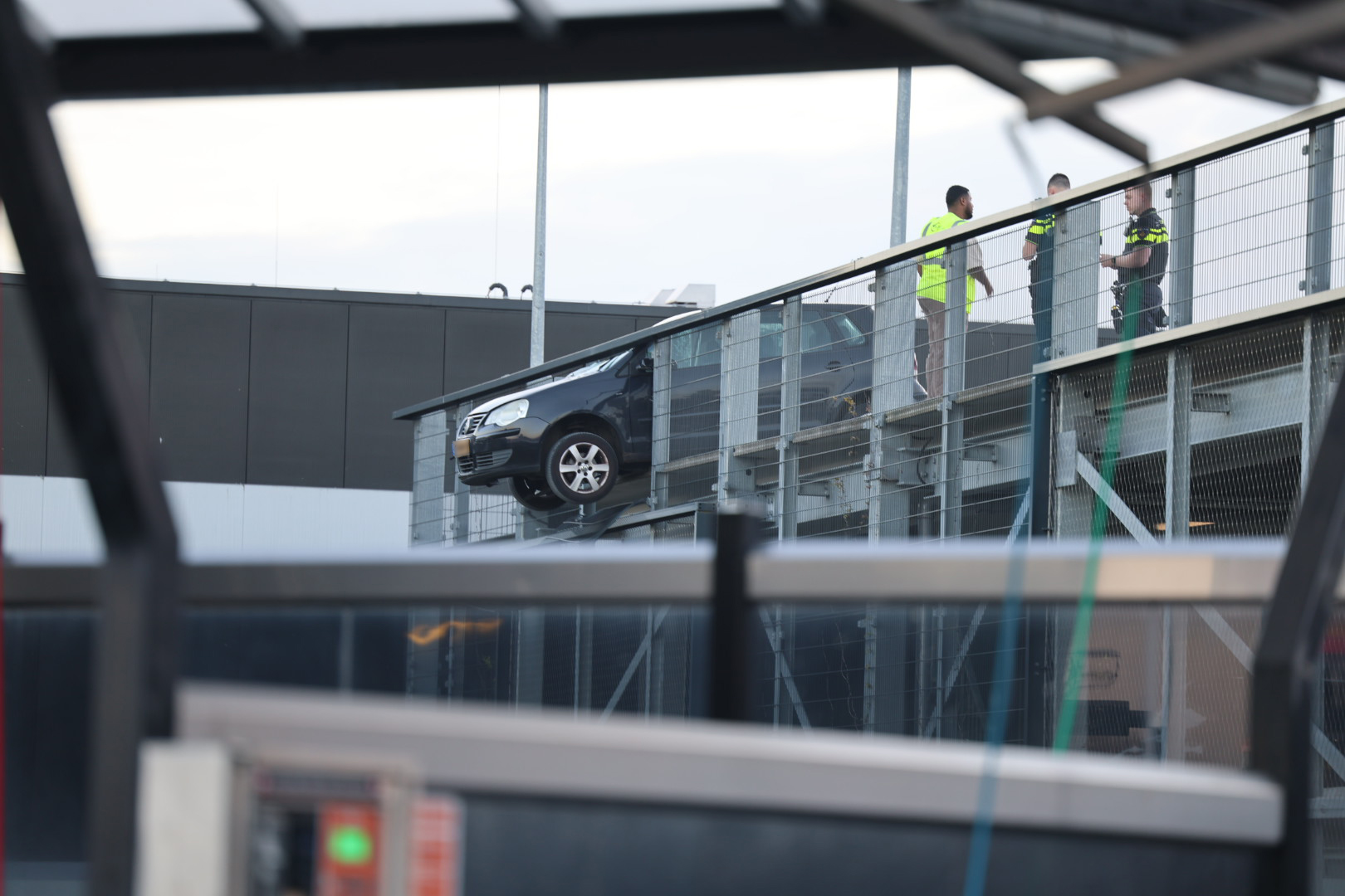 Auto hangt deels over rand van dak parkeergarage