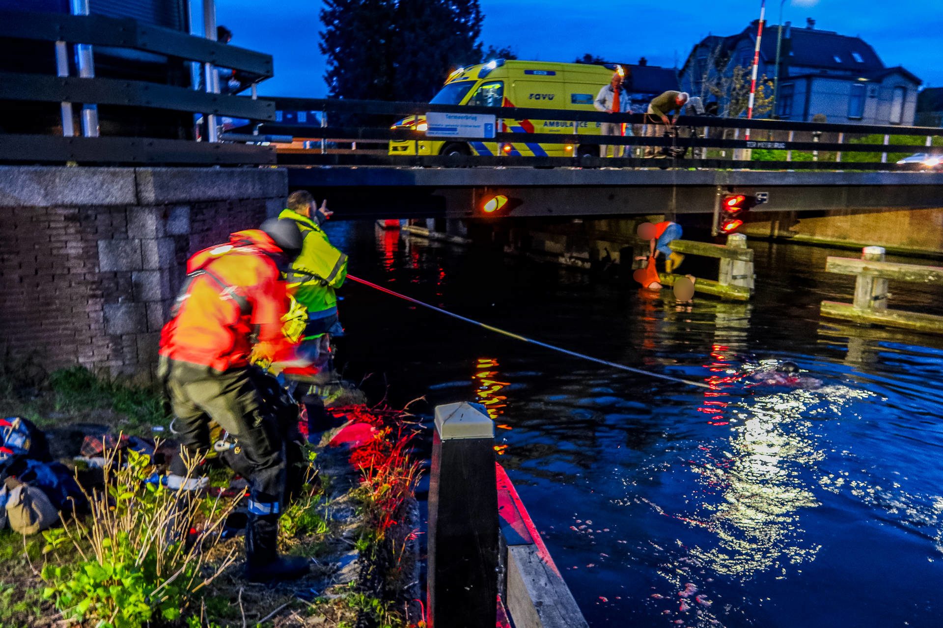Jongeman valt in het water, omstanders schieten te hulp