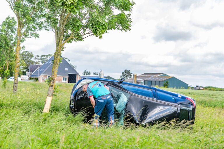 Auto op z’n kant na botsing tegen boom