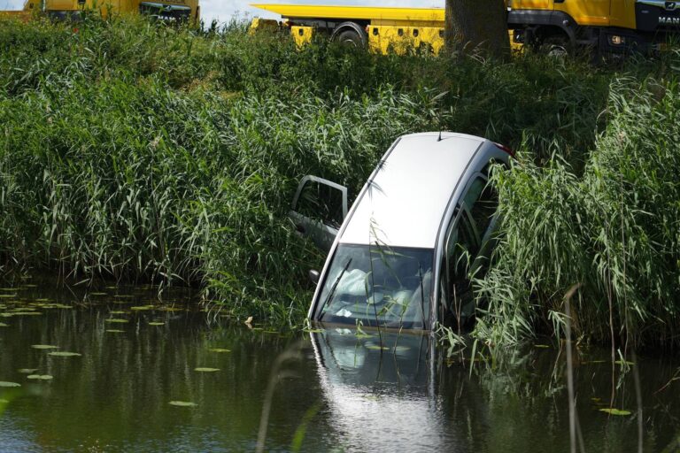 Bedrijfswagen belandt na botsing op zijkant in sloot