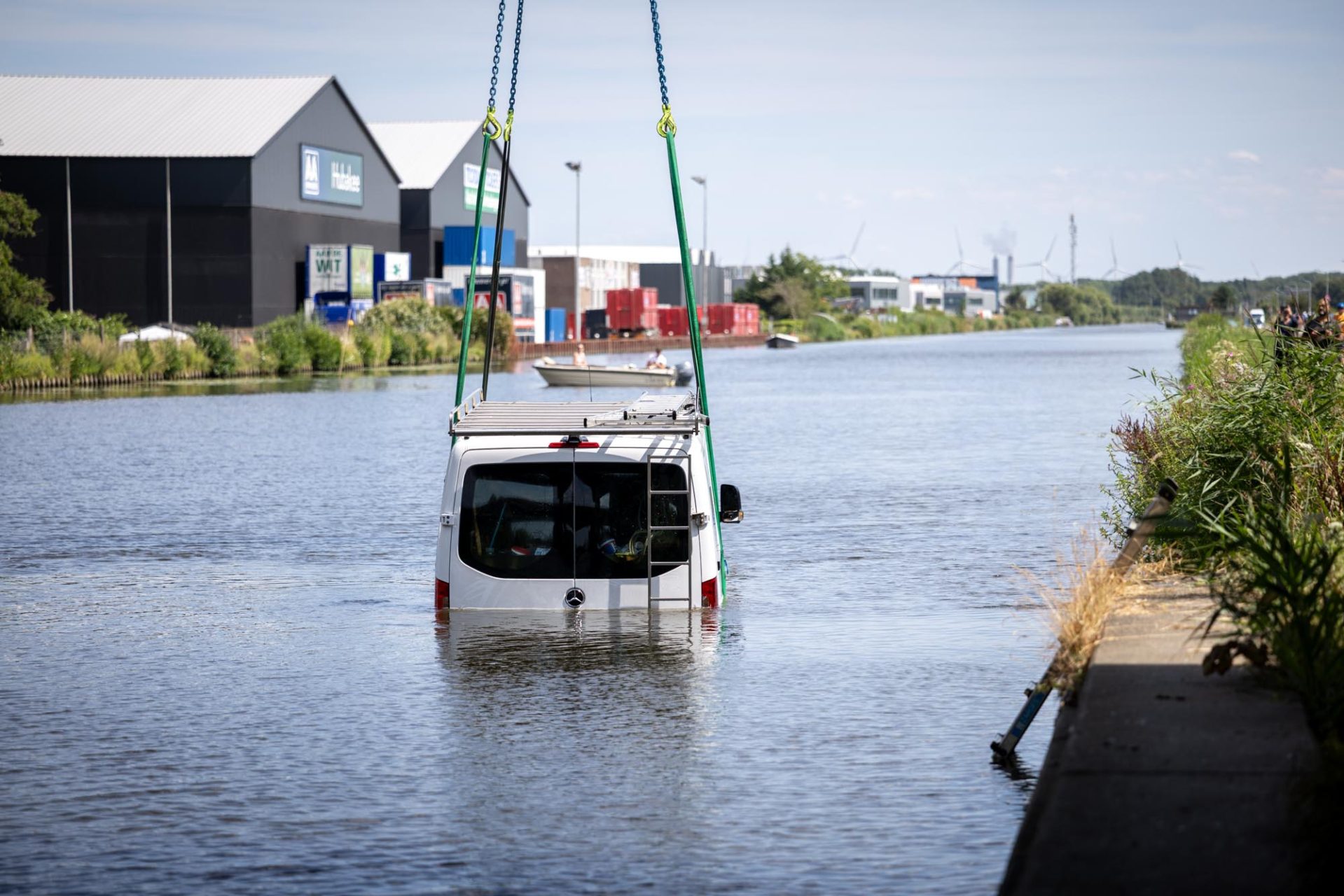 Duikers en kraan hijsen elektrische werkbus na grote bergingsactie uit het water