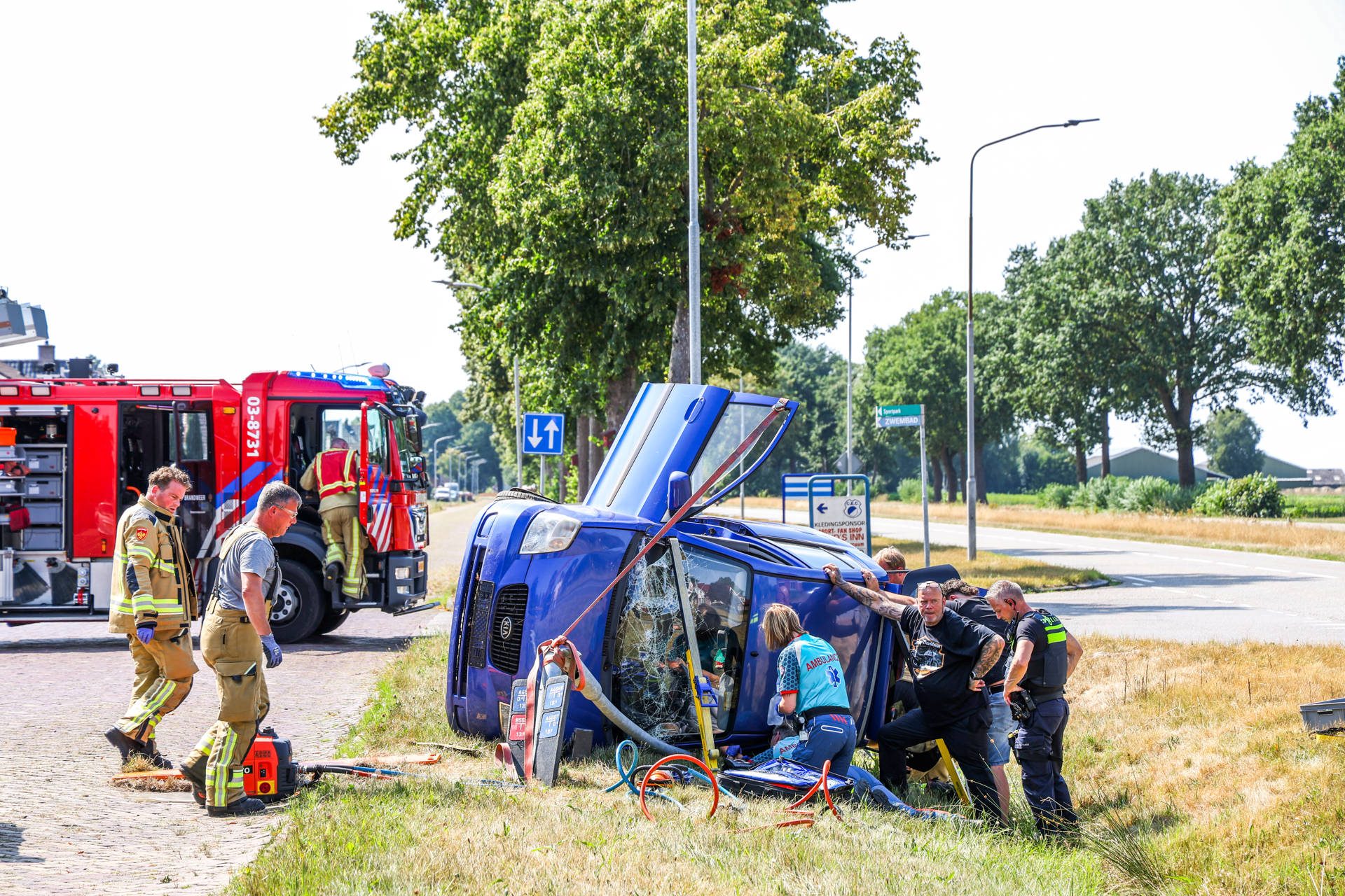 Auto raakt van de weg en belandt op de zijkant, inzittende raakt bekneld