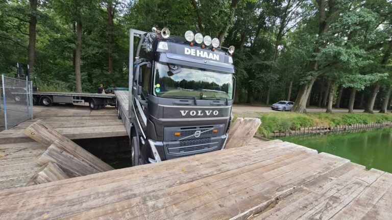 Vrachtwagen zakt door brug en hangt boven gracht