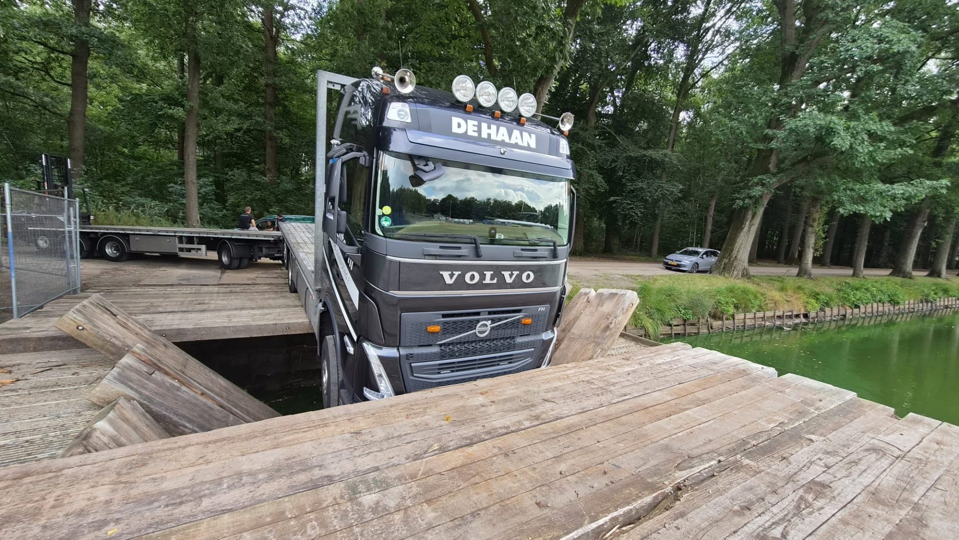 Vrachtwagen zakt door brug en hangt boven gracht