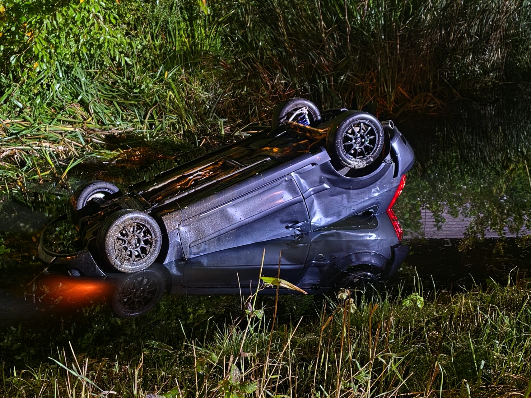 Auto rijdt van dijk en belandt op z’n kop in water