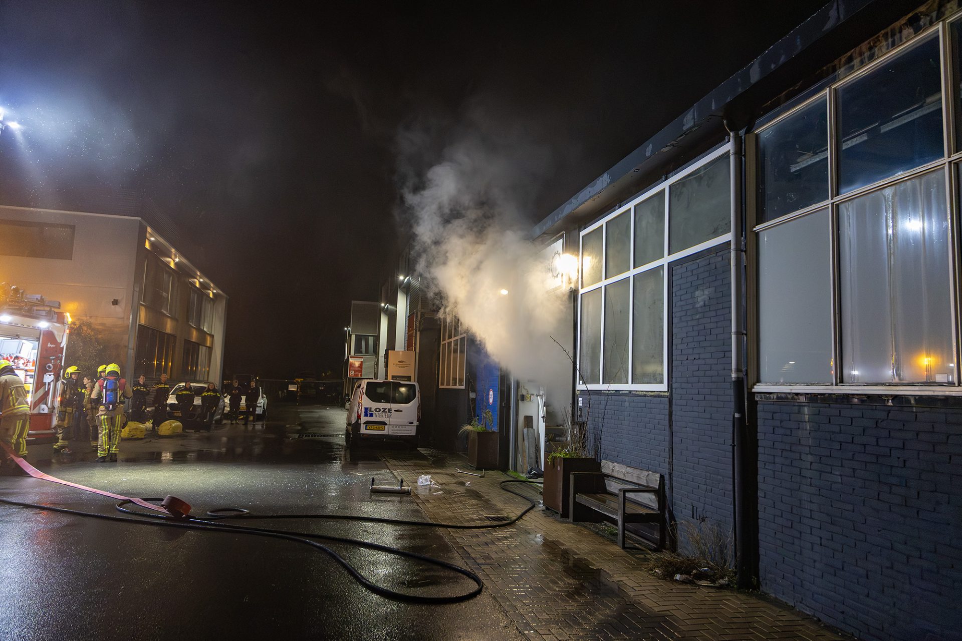 Vlammen zichtbaar achter ramen bedrijfspand, agent gewond bij inslaan autoruit