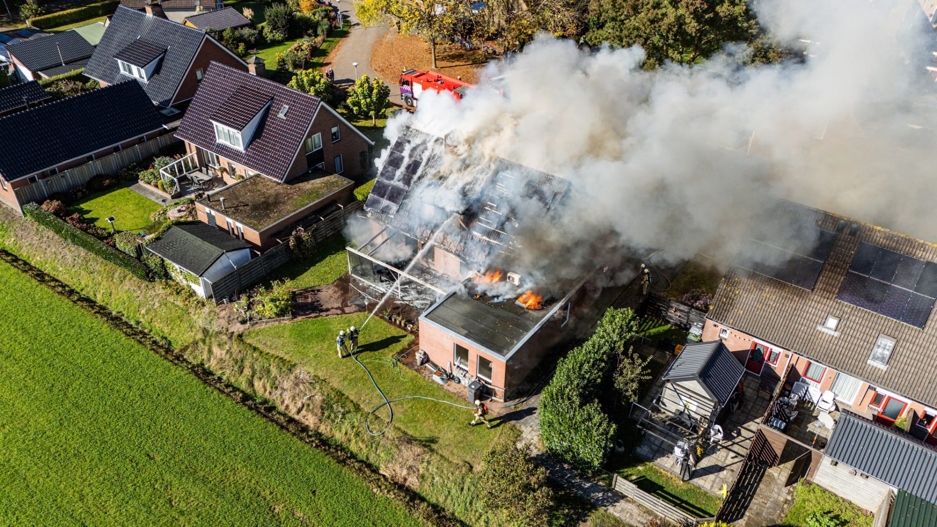 Vlammen slaan uit dak bij uitslaande woningbrand