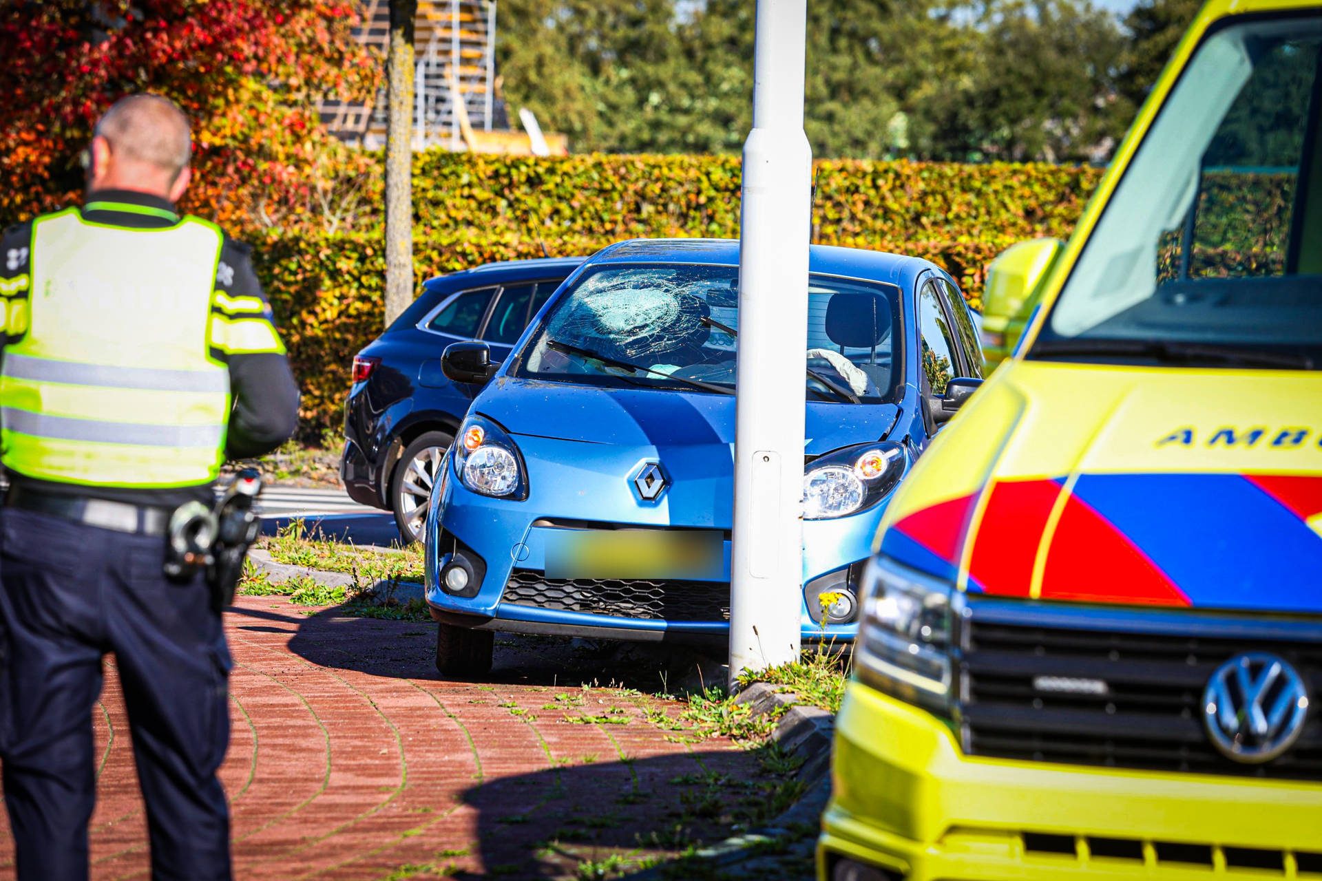Auto ramt paal, vrouw zonder gordel knalt tegen voorruit